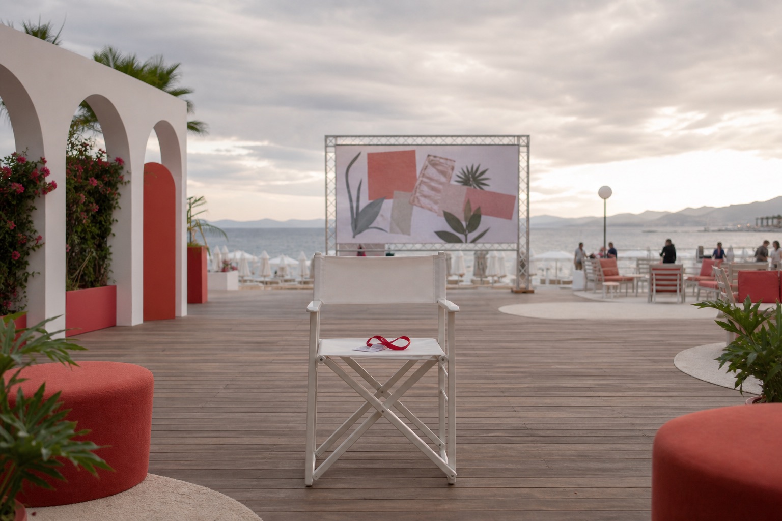 A quiet Cannes beach activation with an empty chair facing a muted event screen